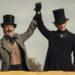 Two men in 19th-century outfits with top hats cheer, raising their gloved hands together.