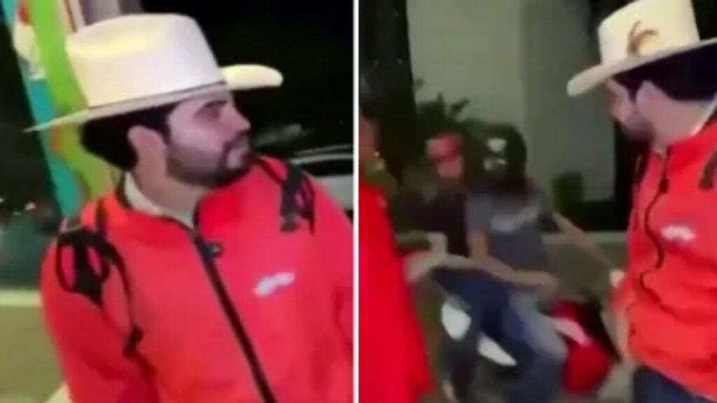 Two men in red jackets and white hats stand on a sidewalk at night, talking with a bystander presence in the background.