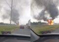 Vehicle burning on the highway with large black smoke rising from the flames and nearby traffic observing the scene.