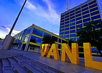 Exterior view of a modern university building with large yellow 'UANL' letters on the steps